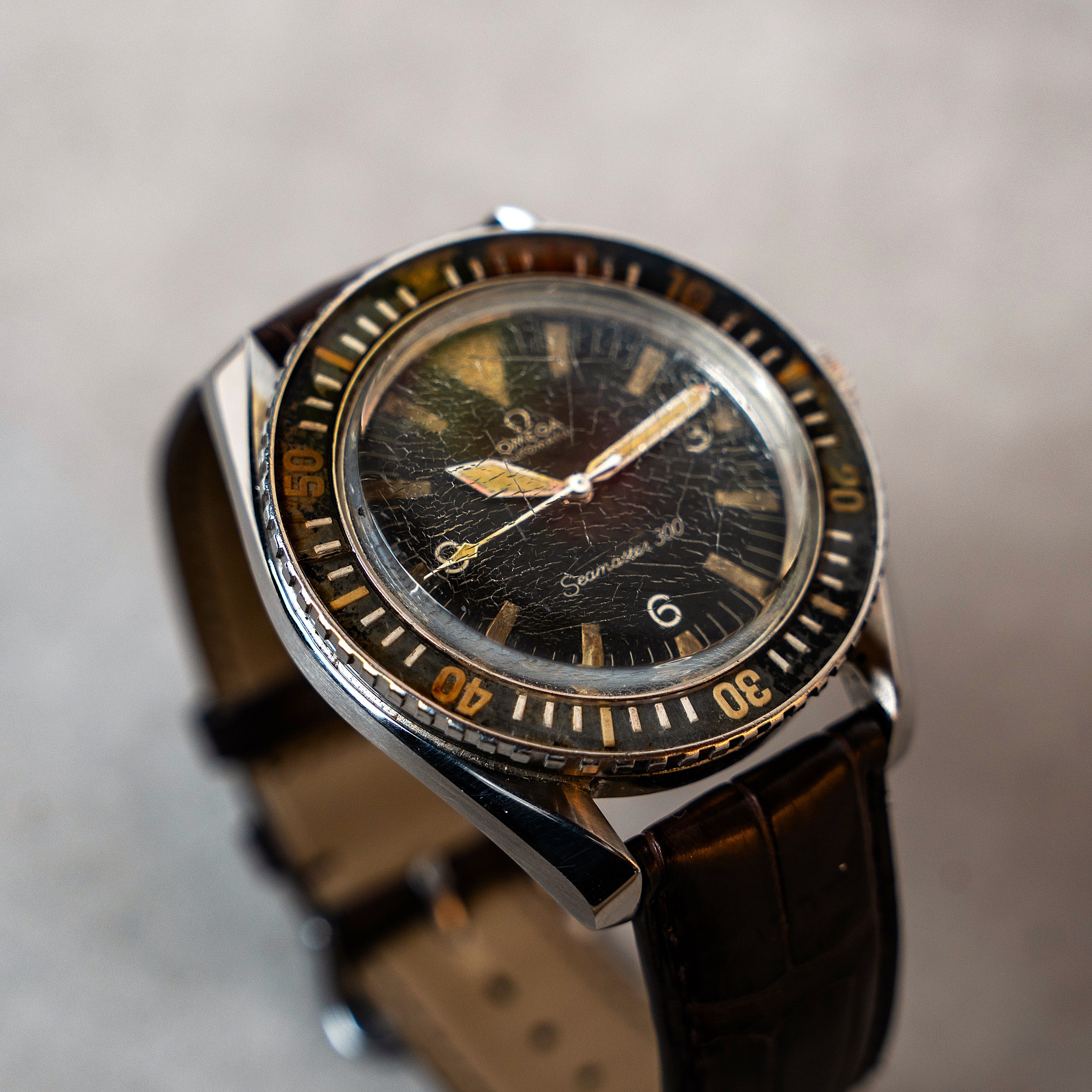 Omega Seamaster 300 automatic original vintage watch with Bakelite bezel the big triangle index at 12 o'clock  and dagger shaped hands and a beautiful patina all around 3/4 angle view